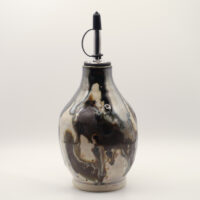 Ceramic oil bottle with swirling black, brown and cream glaze, unglazed base and metal pourer spout with black cap