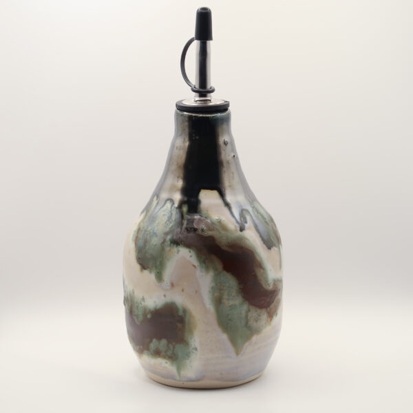 Ceramic oil bottle with a metal pour spout and black cap, glazed in cream with black, sage green and brown drips