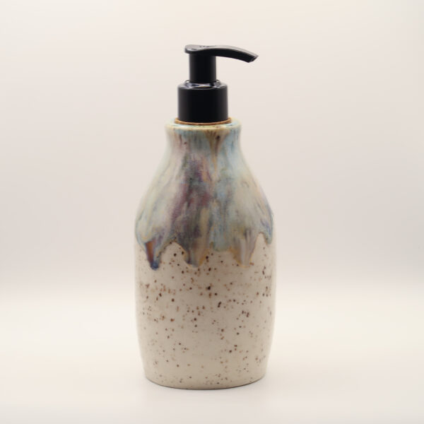 Ceramic soap dispenser in speckled cream glaze with a drippy blue, purple and amber top and a black pump