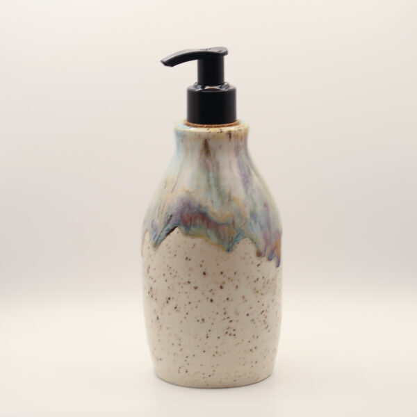 Ceramic soap dispenser with black pump, speckled cream glaze below a dripping blue, purple and amber glaze at the top