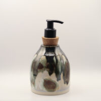 Ceramic soap dispenser with black, green and brown drips over cream glaze, a cork stopper and black pump