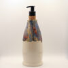 Ceramic soap dispenser in cream glaze with drippy blue, orange and tan glaze on top, black pump and cork collar