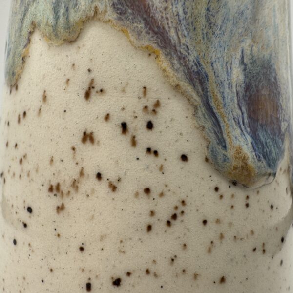 img_7926 Close-up of a soap bottle's cream speckled glaze with a drip of blue, purple and amber glaze flowing down from the top