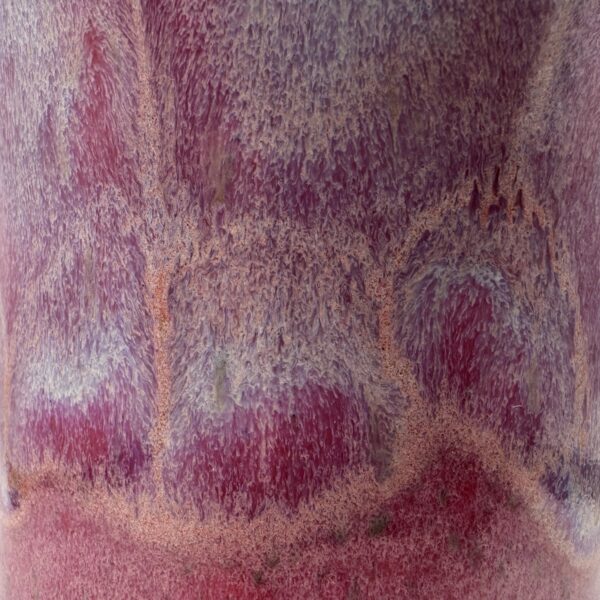 Close-up of a cup's glaze surface, mottled raspberry red, pink and lilac with speckled peach drips